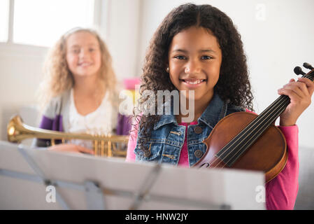 Lächelnde Mädchen posiert mit Violine und Trompete Stockfoto