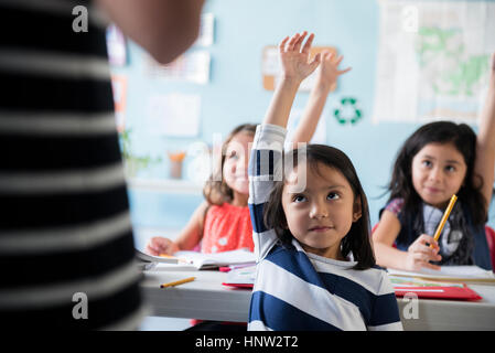 Mädchen, hob die Hand für Lehrer im Klassenzimmer Stockfoto