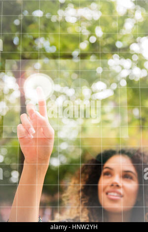 Gemischte Rennen Frau zeigt zum virtuellen Bildschirm im freien Stockfoto