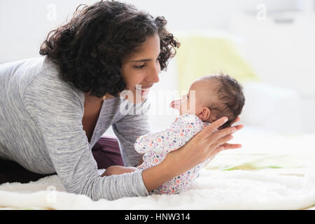 Hispanische Mutter auf Bett Baby Tochter hielt Stockfoto