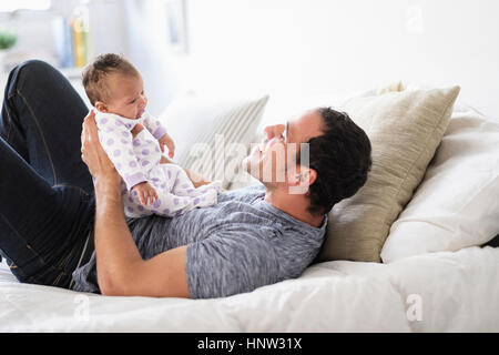 Hispanische Vater mit Tochter auf Bett spielen Stockfoto