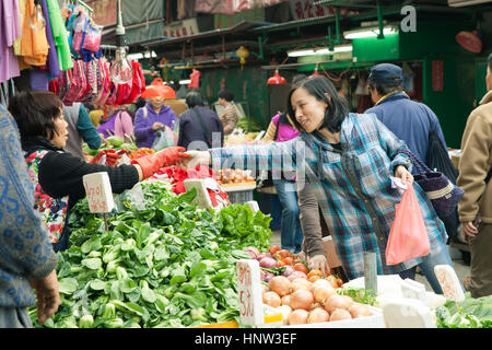 HONG KONG - 17. Februar 2014: Frau kaufen Gemüse in den Straßenmarkt, Hong Kong, 17. Februar 2014. Stockfoto