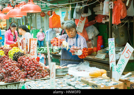 HONG KONG - 17. Februar 2014: Obst-Verkäufer schneidet die Trauben an den Straßenmarkt, Hong Kong, 17. Februar 2014. Stockfoto