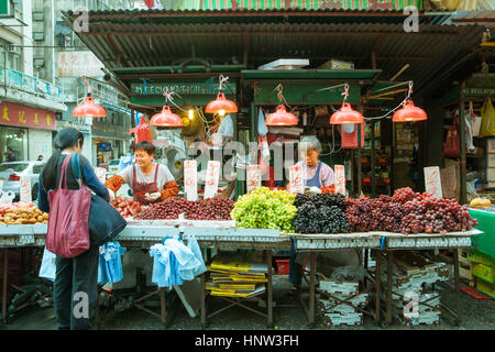 HONG KONG - 17. Februar 2014: Frau kaufen Obst auf dem Straßenmarkt, Hong Kong, 17. Februar 2014. Stockfoto