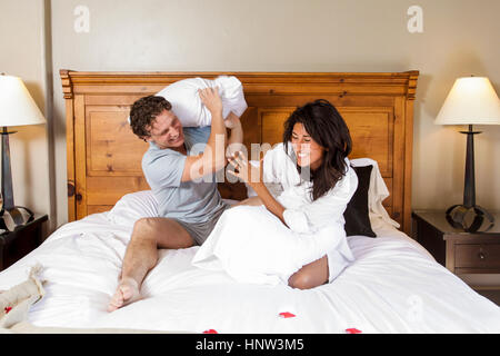 Verspielte Paare, die Kissen zu kämpfen, auf Bett Stockfoto