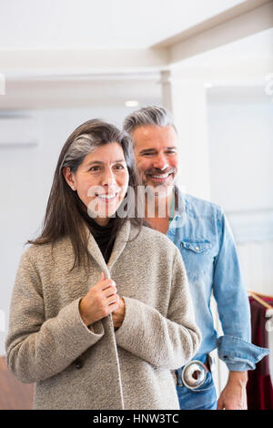 Mann beobachtete Frau Mantel im Store prüfen Stockfoto
