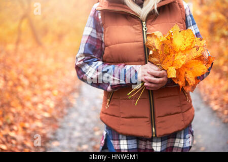 Frau im Freien stehen, halten Herbstlaub, Mittelteil Stockfoto