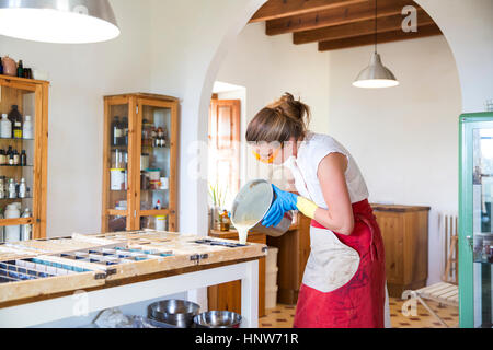 Junge Frau strömenden Flüssigkeit Lavendel Seife in Formen in handgemachte Seife Werkstatt Stockfoto