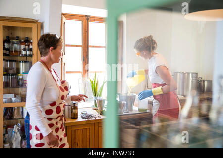 Junge Frau strömenden Flüssigkeit Lavendel Seife in Schüssel in handgemachte Seife Werkstatt Stockfoto