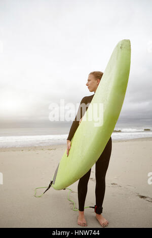 Weibliche Surfer mit Surfbrett Rückblick von Rockaway Beach, New York, USA Stockfoto