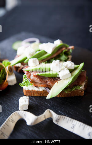 Fleisch, Feta und Avocado belegte Brötchen auf Schiefer Stockfoto