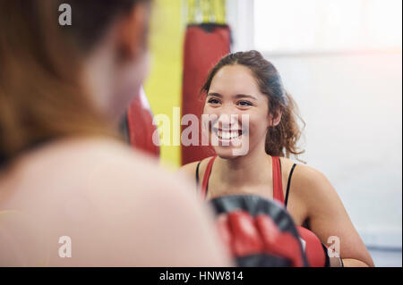 Stanzen Sie über Schulter Blick auf Boxerin training, Teamkollegen Stanzen mitt Stockfoto