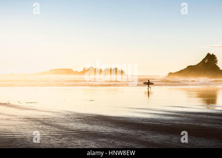 Männliche Surfer mit Surfbrett auf Long Beach, Pacific Rim National Park, Vancouver Island, British Columbia, Kanada Stockfoto