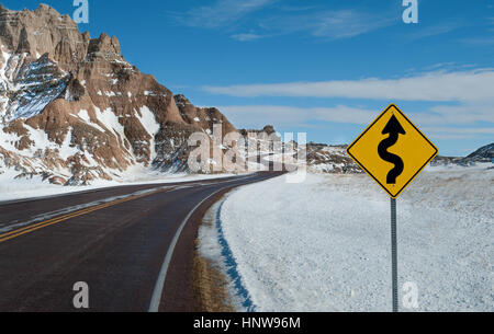 Scharfe Kurven Warnzeichen: Ein Schild warnt vor eine kurvenreiche Straße voraus an einem Wintertag im Badlands National Park. Stockfoto