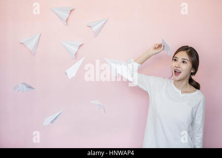 Junge Frau mit weißem Papierflugzeuge Stockfoto