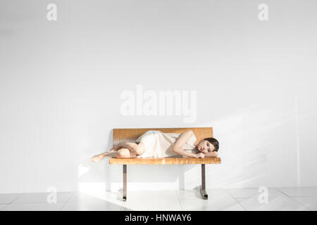 Junge Frau depressiv auf Bank liegend Stockfoto