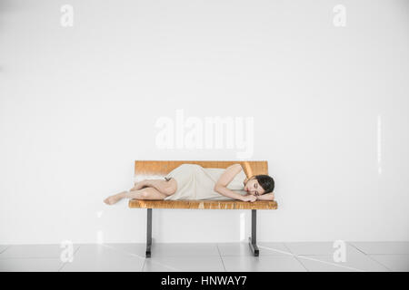 Junge Frau depressiv auf Bank liegend Stockfoto