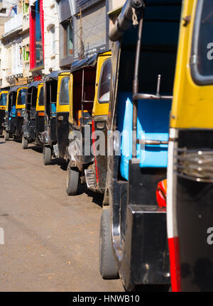 Gelb schwarz Rikschas (Tuk Tuk) aufgereiht in der Straße von Udaipur, Rajasthan, Indien. Stockfoto