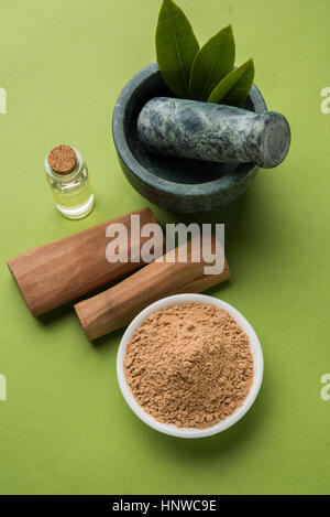 Chandan oder Sandelholz Pulver mit traditionellen Mörtel, Sandelholz Sticks, Parfüm oder Öl und grünen Blättern. selektiven Fokus Stockfoto