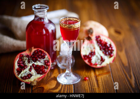 süße Granatapfel Frucht alkoholische herzlich in die Karaffe mit einem Glas auf einem dunklen Tisch Stockfoto