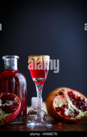 süße Granatapfel Frucht alkoholische herzlich in die Karaffe mit einem Glas auf einem dunklen Tisch Stockfoto