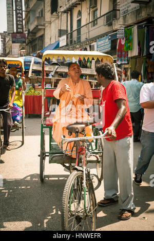 Neu-Delhi, Indien - 17. September 2014: Religiöser Mann in orange Gewand erklärt Ziel der Rikscha, New Delhi, Indien. Stockfoto