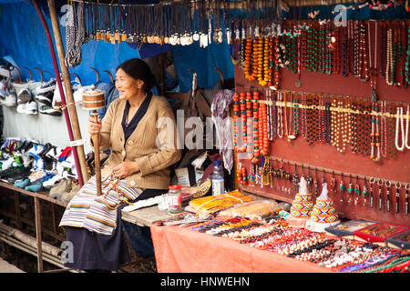 Dharamsala, Indien - 28. September 2014: tibetischer Frau beten mit traditionellen Hand Gebetsmühle auf dem Straßenmarkt, Dharamsala, Indien. Stockfoto