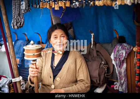 Dharamsala, Indien - 28. September 2014: tibetischer Frau beten mit traditionellen Hand Gebetsmühle auf dem Straßenmarkt, Dharamsala, Indien. Stockfoto