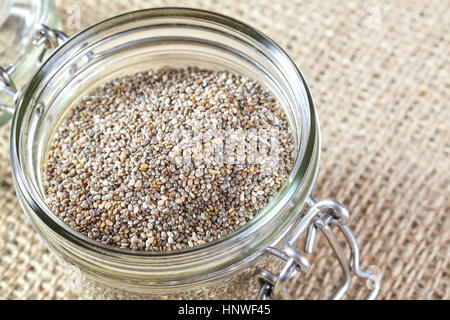 Nahaufnahme von Chia-Samen in einem Glas auf Leinen Hintergrund, Lebensmittel reich an Omega-3-Fettsäuren. Stockfoto