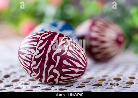 Handbemalte Ostereier, colorised, auf dem Holztisch und bestickte Servietten Stockfoto