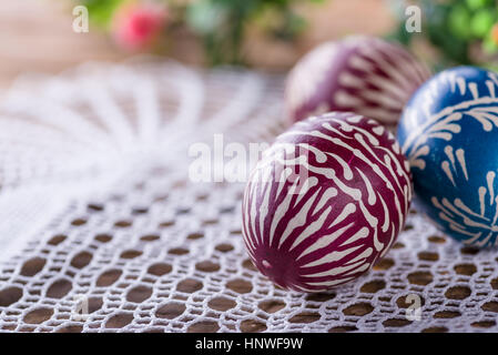 Handbemalte Ostereier, colorised, auf dem Holztisch und bestickte Servietten Stockfoto