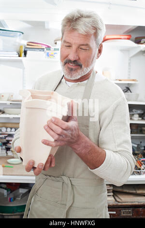 Reifer Mann hält Vase aus Keramik Studio Stockfoto