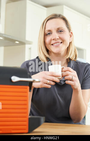 Frau mit Kapsel Kaffeemaschine In der Küche Stockfoto