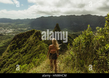 Rückansicht der Frau auf dem Rasen bedeckt Berg, Oahu, Hawaii, USA Stockfoto
