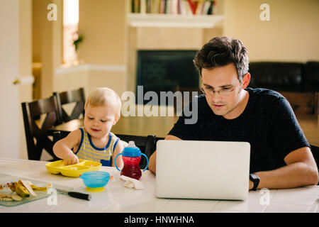 Vater und seinem kleinen Sohn sitzen am Tisch, Essen, mit Laptop Vater Sohn Stockfoto