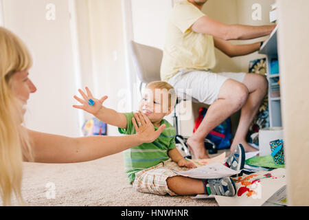 Computer verwenden, während jungen Sohn im Stock mit Mutter spielt Vater Stockfoto