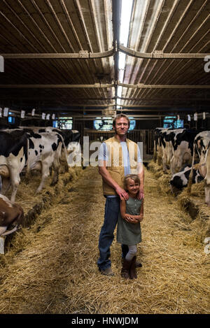 Porträt von Bauer und Tochter im Kuhstall Stockfoto