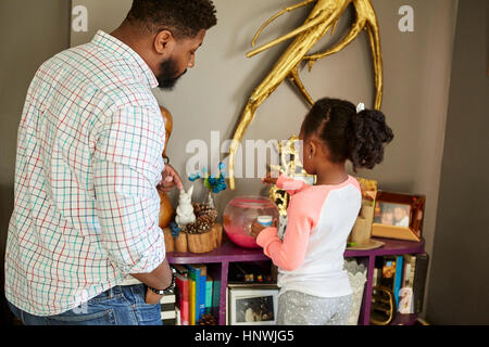 Vater beobachtete Tochter füttere Fische im Goldfischglas Stockfoto