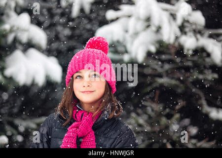 Mädchen in Rosa Mütze blickte zu fallenden Schnee Stockfoto