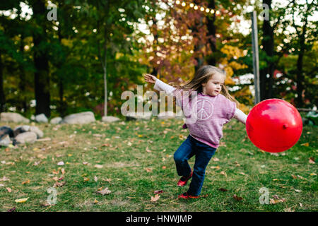 Mädchen spielen mit roten Ballon im Garten Stockfoto