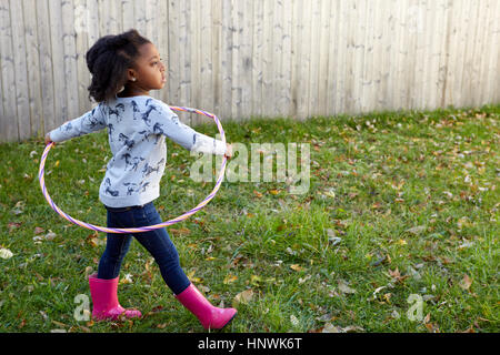 Niedliche Mädchen spielen im Garten mit Kunststoff hoop Stockfoto