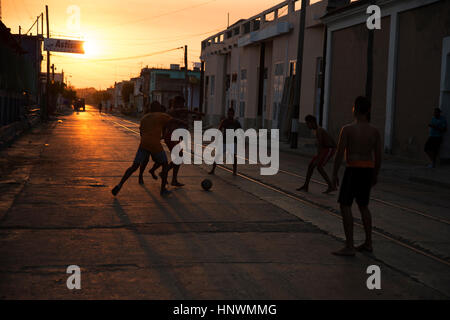 Gruppe von kubanischen Jugendlichen spielen Fußball auf der Straße bei Sonnenuntergang in Cienfuegos, Kuba Stockfoto