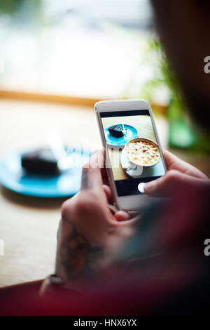 Menschen nehmen Foto von Kuchen auf heiße Schokolade mit smartphone Stockfoto