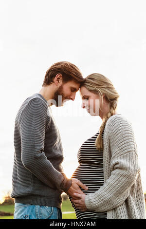 Paar Frau schwanger Bauch, Kopf an Kopf im Feld Landschaft berühren Stockfoto
