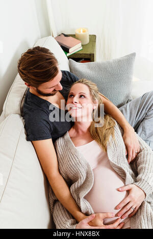 Schwanger Mitte erwachsenes paar berühren schwanger Bauch auf sofa Stockfoto