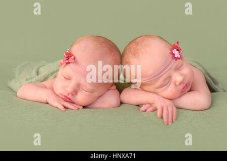 3 Wochen alt eineiige Zwillinge schlafen auf einem grünen Hintergrund Stockfoto