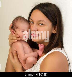 Junge Mutter von gemischter Herkunft ihren 1 Woche alt neugeborenen Jungen im Arm halten Stockfoto