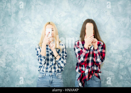 Freundinnen in karierten Hemden mit Smartphones auf die blaue Wand-Hintergrund Stockfoto