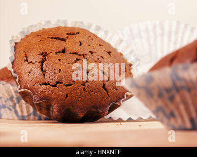 Schoko-Muffin. Frisch gebackene Schokoladen-Muffins in Papier Backen Form auf Holzbrett Stockfoto