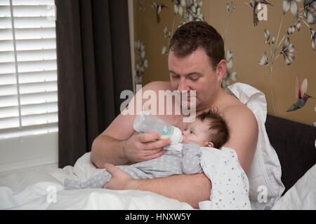 Papa Fütterung Baby im Bett Stockfoto